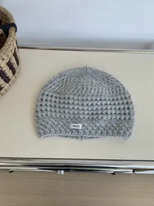 Grey hollow-out knit beanie detail view, showing soft wool texture and a minimalist label.