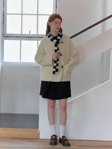 Detail view of the stylish black and white color block knitted scarf worn by model.