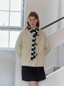Detailed view of the black and white striped knitted scarf worn by a model indoors.