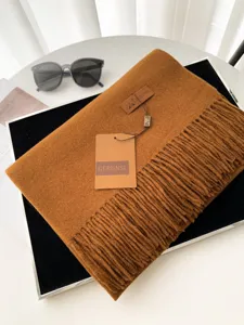 Vista dettagliata della sciarpa invernale marrone finto cashmere con frange ed etichetta di marca.