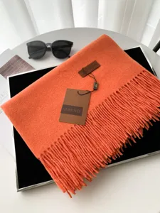 Dettaglio sciarpa invernale arancione effetto cashmere, morbida e spessa da donna con frange.
