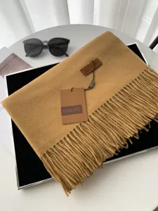Dettaglio sciarpa invernale effetto cashmere cammello, morbida trama con eleganti frange.