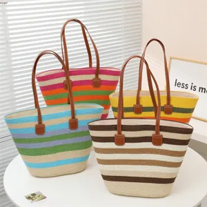 Vista detallada de bolsos tote de paja multicolor de moda con asas de cuero marron.