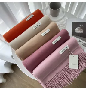 Detailed close-up view of colorful cashmere winter scarves with fringe on a white table.