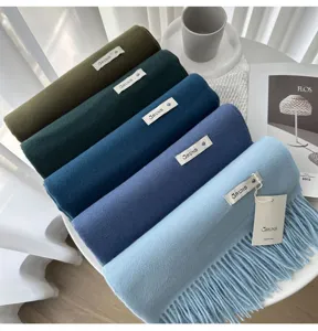 Detailed view of rolled cashmere feel winter scarves in assorted colors with fringed edges.