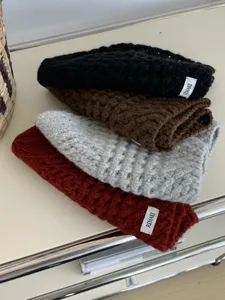 Close-up of stylish hollow-out knitted beanies in multiple colors displayed nicely on a table.