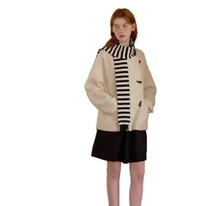 Women's beige duffle coat matching black skirt and striped scarf, chic winter outfit.