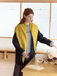Vista detallada del pañuelo triangular de punto amarillo combinado con abrigo en interior.