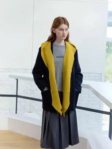 Detailed view of the cozy knitted shawl scarf and stylish layered outfit in indoor setting.