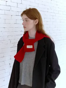 Dettaglio di sciarpa in maglia rossa con trama morbida e design elegante per calore invernale.