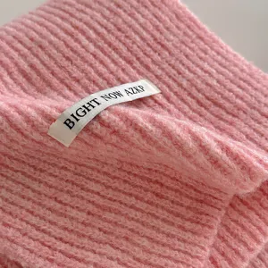Primo piano di sciarpa in lana lavorata a maglia rosa, scaldacollo invernale morbido.