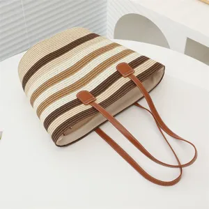Vista detallada del elegante bolso de paja a rayas, con diseño color-block y asas resistentes.