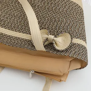 Close up of large capacity summer beach straw tote bag with bow and zipper closure.