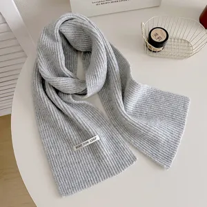 Dettaglio della sciarpa in maglia grigia, accogliente trama a costole per l'inverno, morbido accessorio.
