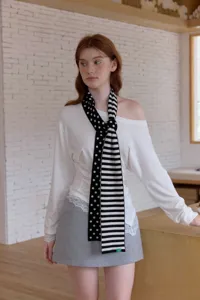 Knit scarf detail showing soft black and white polka dot and stripe pattern design texture.