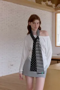 Detailed close-up of a stylish black and white knit scarf with polka dot and stripe patterns.