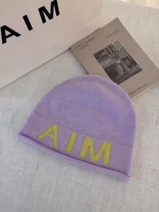 Detail shot of a soft wool-blend knitted beanie in pastel purple with bold yellow letters.