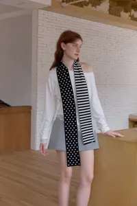 Cozy black and white knit winter scarf featuring chic polka dot and stripe patterns.