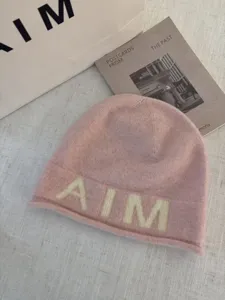 Pink knit beanie hat detail view, warm wool blend winter slouchy cap with soft texture.
