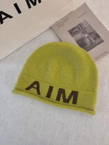 Detailed view of soft wool blend knitted beanie hat in lime green with prominent AIM letters.
