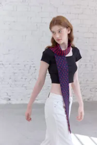 Close-up detail shot of the stylish knitted scarf with red and blue polka dot and stripe design.