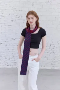 Detailed shot of a stylish narrow knitted scarf featuring a chic dot and stripe pattern.