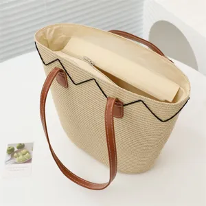 Detailansicht der großen Strohgewebe-Tasche mit braunen Griffen für den Sommer am Strand.