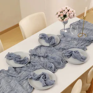 Close-up details of dusty blue cheesecloth table runner and matching napkins for party decor.