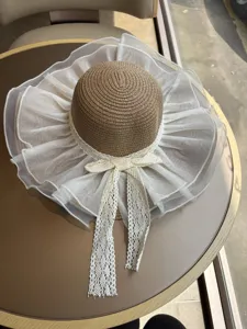 Breitkrempiger Strohhut mit elegantem weißem Tüll und Spitzen-Schleifendetail für den Strand.