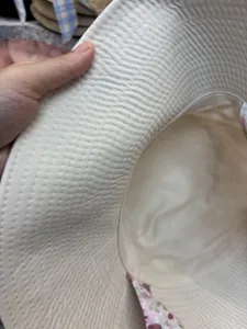 Close-up detail of beige bucket hat showing fine brim stitching and floral inner lining.