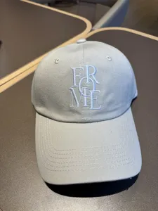 Close-up detail of the light blue casual baseball cap featuring white embroidered lettering.