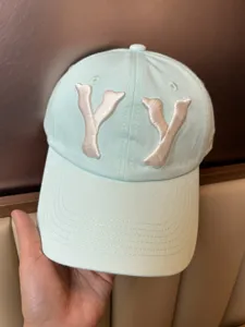 Mint green baseball cap detail view, featuring white embroidered letter YY and classic cotton fabric close-up.