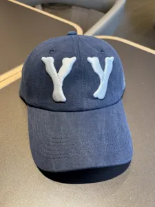 Detailed view of dark blue washed vintage baseball cap with white 3D embroidery YY letters.