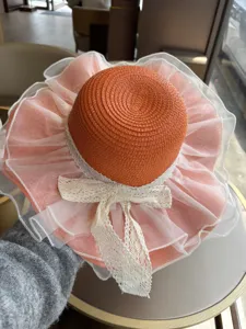 Stilvoller orangefarbener Damen-Stroh-Sonnenhut mit weißer Spitzenschleife und Netzrand.