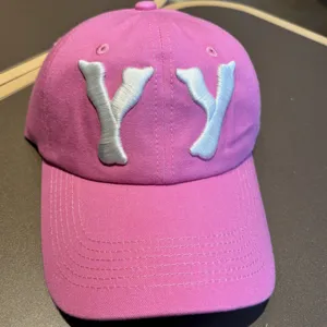 Pink washed baseball cap with embroidered YY letters, casual streetwear style, stylish accessory.