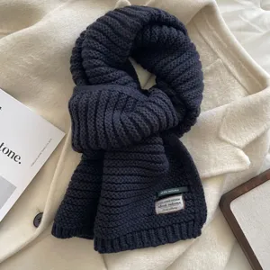 Detailed shot of a cozy dark blue knit winter scarf, thick warm woolen texture for women.