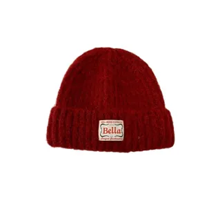 Red knitted beanie hat for women, cozy winter pullover wool cap with stylish cloth label.