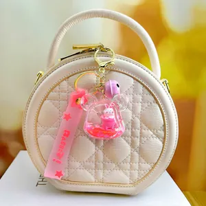 Sac à main rond matelassé chic avec un porte-clés lapin mignon rempli de liquide.