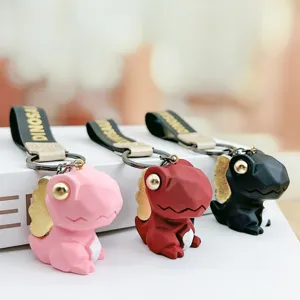 Detailopname van schattige gefacetteerde dinosaurus sleutelhanger in roze, rood en zwart.