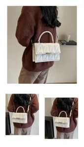 White quilted shoulder bag with top handle and metal clasp, stylish crossbody bag for women.