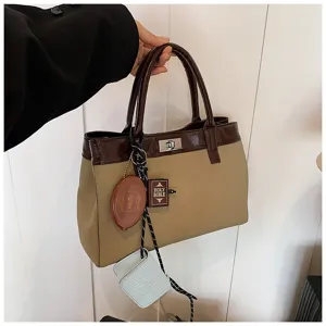 Detail view of stylish two-tone PU leather top-handle handbag with chic decorative pendants.