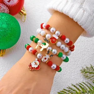 Primo piano di festosi braccialetti natalizi con ciondoli Babbo Natale e renne sul polso.