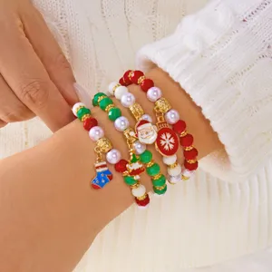 Dettaglio di braccialetti natalizi di perline con ciondoli Babbo Natale indossati al polso.