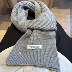 Grey knitted wool blend scarf detail view showcasing handmade label and cute shell button accents.