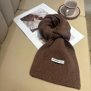 Primo piano della trama della sciarpa in maglia marrone, morbido scaldacollo caldo invernale.