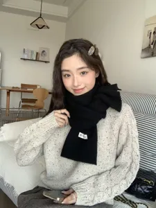 Detailed view of the cozy black knitted winter scarf worn by a model, soft and warm texture.