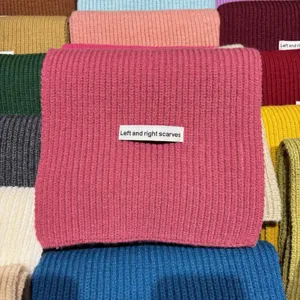 Primo piano di una morbida sciarpa in maglia dai colori vivaci con etichetta tessuta.