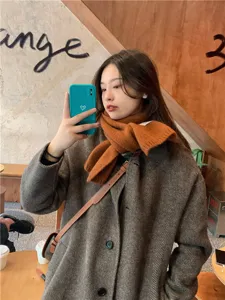 Winter cozy knitted scarf and herringbone coat detail, warm and stylish streetwear look.