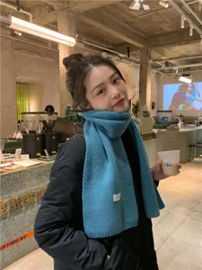 Winter warm knitted scarf close up, soft blue wool texture shown clearly in indoor cafe.