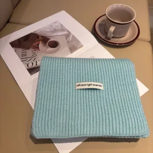 Primo piano sui dettagli della sciarpa in maglia blu morbida, scena piatta invernale accogliente.